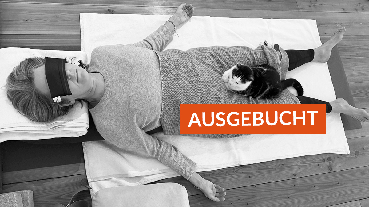 Schülerin in Shavasana, Katze sitzt im Schoß, orangefarbenes °Ausgebucht"-Schild