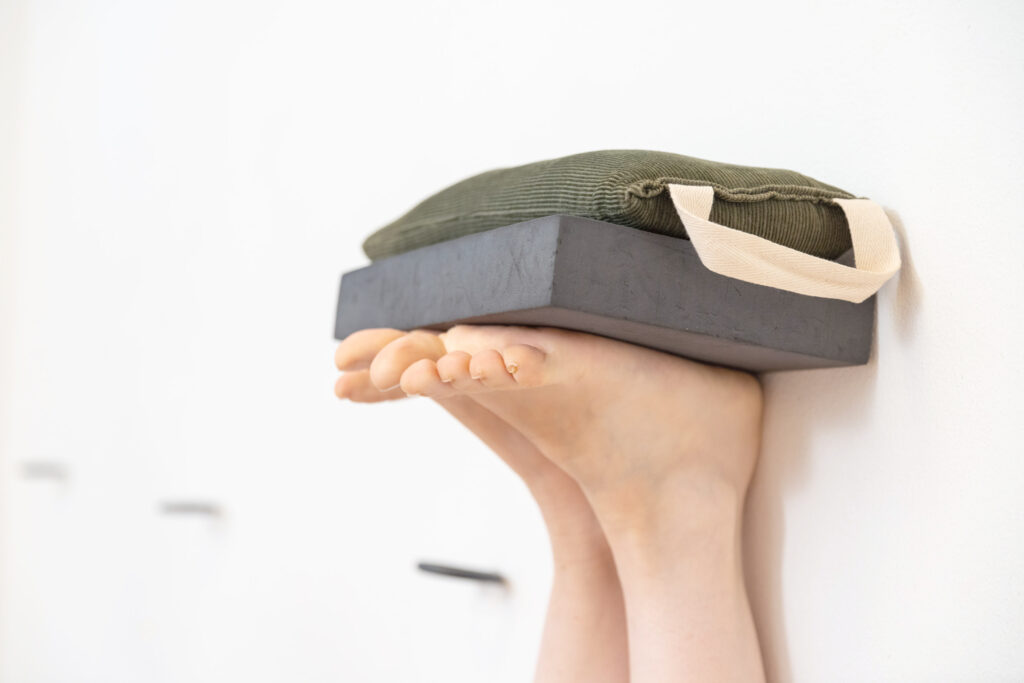 Sandsäckchen und schwarze Platte als Yoga-Hilfsmittel auf einem hochgestreckten Fuß