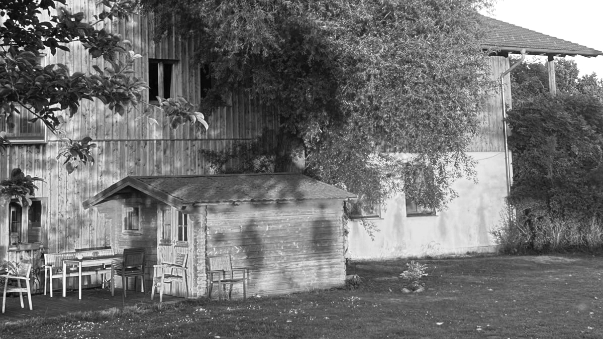 Schwarzweißansicht des Seiminarhauses Holzmannstett mit Baum und Schatten von menschen auf dem Haus