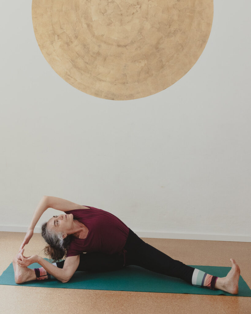 Elisa Bruni im Yogashala-Studio, sie übt Parsva Upavistha Konasana Urdhva Hasta, hinter ihr ein goldener Kreis