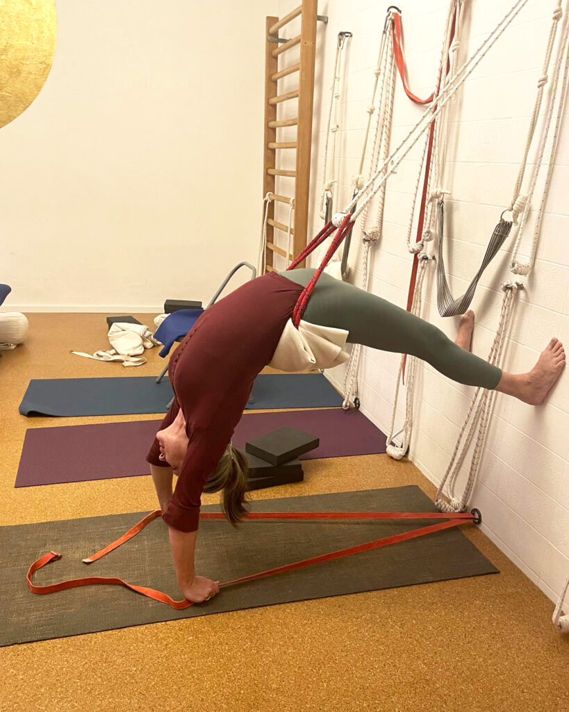 Schülerin übt Rückbeuge im Seil im Yogashala