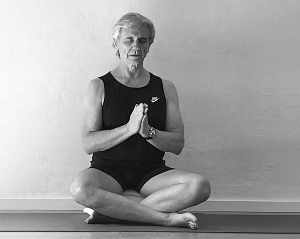 Glenn Ceresoli sitz auf einer Yoga-Matte in Atmanjali Mudra, Schwarzweißbild