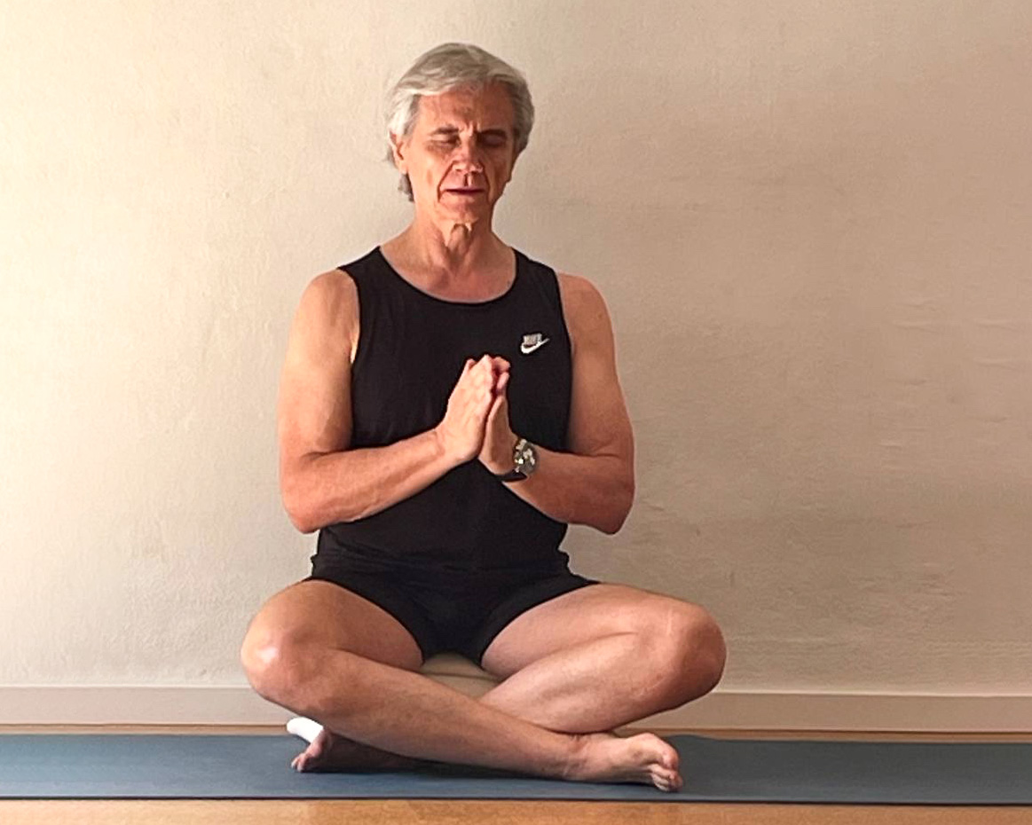 Glenn Ceresoli sitz auf einer Yoga-Matte in Atmanjali Mudra